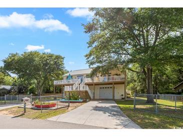 Inviting two-story home with a spacious deck, a white picket fence, and a well-manicured lawn at 3926 Flagg St., Murrells Inlet, SC 29576