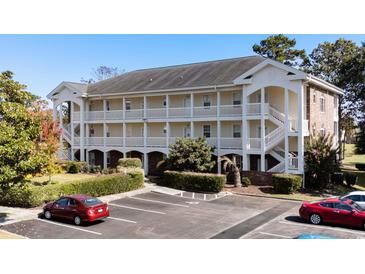Beautiful two-story condo building with white siding, balconies, manicured landscaping, and ample parking at 703 Riverwalk Dr. # 303, Myrtle Beach, SC 29579