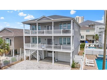Three-story home featuring double balconies, gray siding, a brick driveway, and a well-manicured landscaped perimeter at 204 33Rd Ave. N, North Myrtle Beach, SC 29582