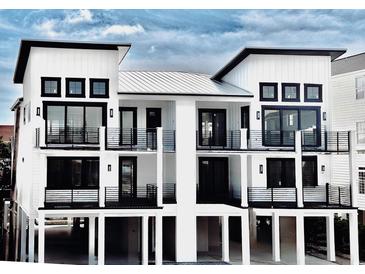 Stunning three-story white beach home featuring modern architecture, black trim, and multiple private balconies at 210 28Th Ave. N, North Myrtle Beach, SC 29582