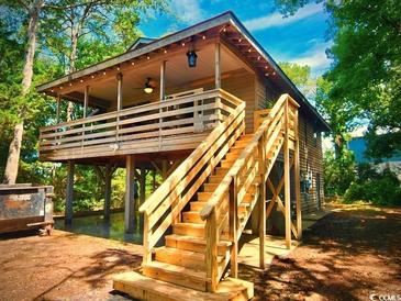 Charming raised beach house with wooden stairs and large covered porch, perfect for relaxing outdoors at 2419 Hilton Dr., North Myrtle Beach, SC 29582