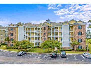 Beautiful multi-story condo building with yellow and brick accents and lush landscaping at 4890 Luster Leaf Circle # 201, Myrtle Beach, SC 29577