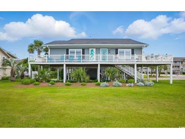 Charming coastal home with a spacious porch, lush landscaping, and a well-manicured lawn at 1705 N Ocean Blvd. N, North Myrtle Beach, SC 29582