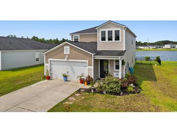 Charming two-story home featuring attached garage, landscaped yard, and lake view at 196 Cypress Tree Loop, Longs, SC 29568