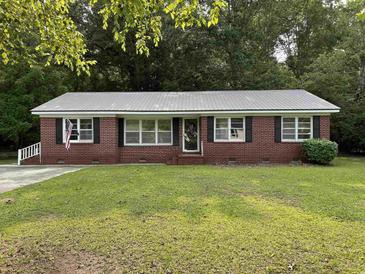 Charming brick home with a well-manicured lawn, gray metal roof, and black shutters at 205 S Oliver Blvd., Hemingway, SC 29554