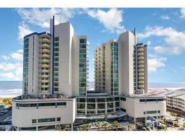 Stunning resort exterior with ocean view, bright blue sky, and lush tropical landscaping at 300 N Ocean Blvd. # 723, North Myrtle Beach, SC 29582