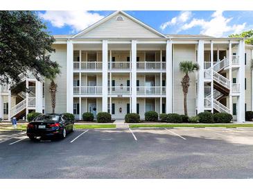 Three-story condo building with white columns, ample parking, and neatly landscaped grounds at 6010 Windsor Green Way # 301, Myrtle Beach, SC 29579