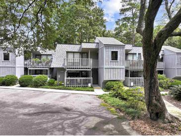 Inviting exterior featuring a townhouse with grey siding and a wooden railed porch surrounded by lush landscaping at 88 Salt Marsh Circle # 22F, Pawleys Island, SC 29585