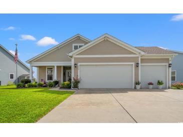 Charming tan home with a two car garage, manicured lawn, and beautiful landscaping at 915 Sorano St., Myrtle Beach, SC 29579