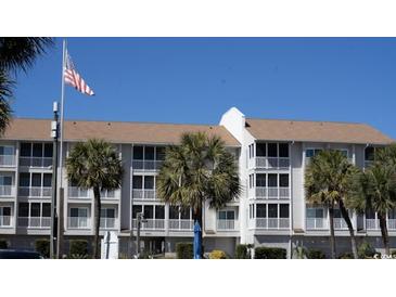 Low-rise condo building with a three-story exterior and a well-maintained facade surrounded by palm trees and the American flag at 9571 Shore Dr. # 318, Myrtle Beach, SC 29572
