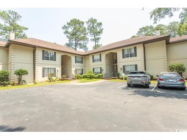 Two-story condo with light beige exterior, black shutters, and ample parking spaces at 108 Pipers Ln. # 108, Myrtle Beach, SC 29575