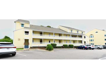 Charming condominium exterior with yellow siding, multiple balconies, and ample parking at 1100 Possum Trot Dr. # D106, North Myrtle Beach, SC 29582