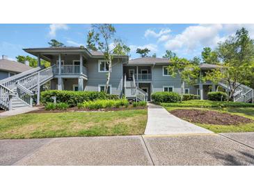 Two-story condo building with gray siding and well-maintained landscaping under a partially cloudy sky at 1221 Tidewater Dr. # 122, North Myrtle Beach, SC 29582