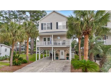 Charming two-story beach house on stilts with palm trees and a well-maintained yard at 327 A Lakeside Dr., Surfside Beach, SC 29575