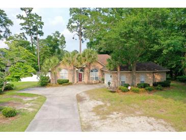Charming brick home with mature landscaping, long driveway, and a well-manicured front yard at 4447 River Rd., Little River, SC 29566
