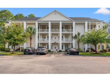 Three-story condo building with white columns and balconies, surrounded by trees and a parking lot at 6000 Windsor Green Way # 104, Myrtle Beach, SC 29579