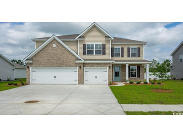 Two-story home with a two-car garage, brick and vinyl siding and a well-manicured front lawn at 7183 Shooting Star Way, Myrtle Beach, SC 29579