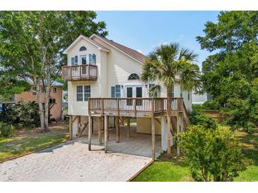Charming beach home featuring a spacious deck, complemented by a well-maintained yard and a convenient ground-level carport at 154 Cedar Point Ave., Murrells Inlet, SC 29576