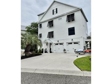 Charming three-story home features white siding, black shutters, and a three-car garage at 17 Carson Creek Dr., Murrells Inlet, SC 29576