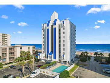 Coastal condo building features a swimming pool, parking, and overlooks an expansive beach with beautiful blue skies at 2609 South Ocean Blvd. # 702, North Myrtle Beach, SC 29582