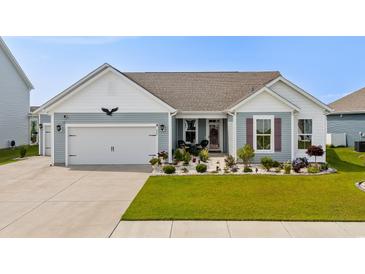Charming single-story home with blue siding, a well-manicured lawn, and an attached two-car garage at 379 Mikita Dr., Surfside Beach, SC 29575