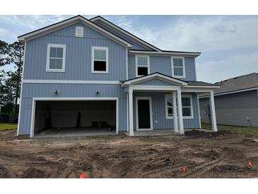 Two-story blue home with a front porch, unfinished landscaping, and a two-car garage at 1039 Laconic Dr., Myrtle Beach, SC 29588