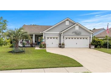 Charming home featuring a two-car garage, well-manicured lawn, and inviting front porch perfect for relaxing at 1833 Lake Egret Dr., North Myrtle Beach, SC 29582