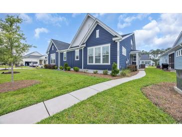 Charming blue two-story home with white trim, manicured lawn, and paved walkway on a sunny day at 2080 Silver Island Way, Murrells Inlet, SC 29576