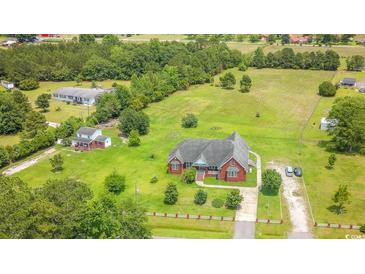 An aerial view of a red brick house with large lawns and mature trees around the home at 2191 Jasmine Rd., Loris, SC 29569