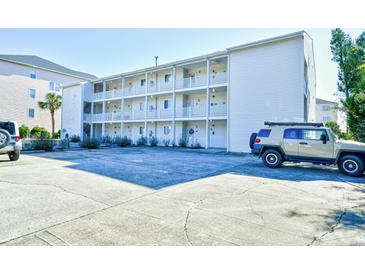 Condominium building featuring white siding, balconies, and ample parking at 3308 S Ocean Blvd. # 2_B, North Myrtle Beach, SC 29582