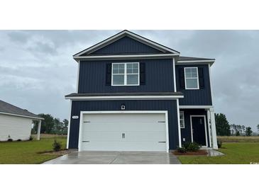 Charming two-story home with a white garage door, blue siding, and a well-manicured lawn at 3579 Ashridge Way, Conway, SC 29526