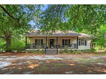 Charming home with a covered front porch and rocking chairs, set amidst mature trees at 8506 Old Nichols Hwy., Nichols, SC 29581