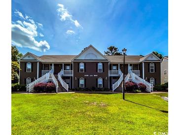 Charming townhome featuring a well-manicured lawn and appealing architectural details, including white staircases and a brown facade at 1101 Peace Pipe Pl. # 104, Myrtle Beach, SC 29579