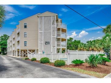 Attractive condo building with white fencing, landscaping, and exterior staircases and balconies at 211 N Hillside Dr. # 204, North Myrtle Beach, SC 29582