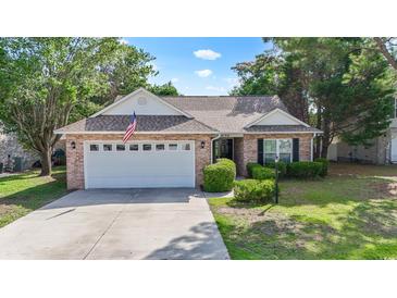 Charming brick home featuring an attached garage, a well-maintained lawn, and manicured landscaping at 4196 Ravenwood Dr., Little River, SC 29566
