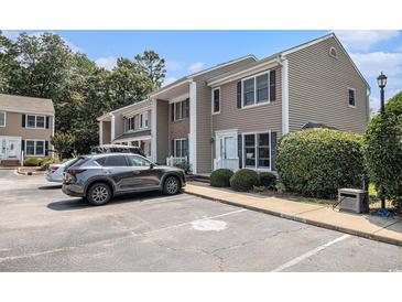 Tan townhouse with black shutters and a parking area in front of the building surrounded by mature trees and blue skies at 6702 Jefferson Pl. # C6, Myrtle Beach, SC 29572
