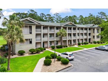 Three-story condo building with lush landscaping and well-maintained parking area at 562 Blue Stem Dr. # 54-F, Pawleys Island, SC 29585