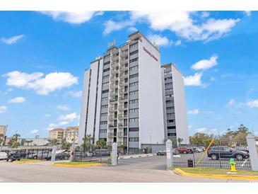 Exterior shot of the Breakers Resort condominium tower with a parking lot and palm trees in the background at 601 Mitchell Dr. # 207, Myrtle Beach, SC 29577