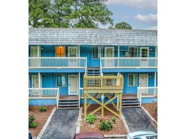 Charming blue exterior building with private balconies and well-maintained landscaped walkway at 601 Putters Ln. # H209, Little River, SC 29566