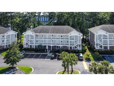 Three-story condo building with white balconies, ample parking, and lush landscaping at 698 Riverwalk Dr. # 304, Myrtle Beach, SC 29579