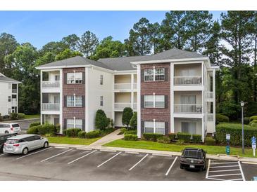 Exterior of condo building with brick accents, white siding, and multiple balconies overlooking a landscaped courtyard at 1302 River Oak Dr. # 4B, Myrtle Beach, SC 29579