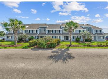 Charming condo complex with well-manicured landscaping and palm tree accents under a bright blue sky at 1890 Colony Dr. # 17L, Surfside Beach, SC 29575