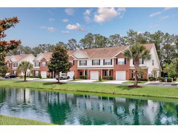 Attractive townhomes nestled alongside a tranquil pond with lush greenery and reflections on a beautiful day at 265 Connemara Dr. # D, Myrtle Beach, SC 29579