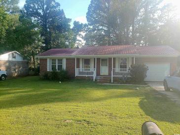 Charming brick home with a red metal roof, inviting porch, and a lush green front lawn at 3909 Mallard Circle, Myrtle Beach, SC 29579