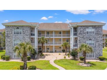 Charming condo complex featuring stone accents, lush landscaping, and sunny skies at 4687 Wild Iris Dr. # 303, Myrtle Beach, SC 29577