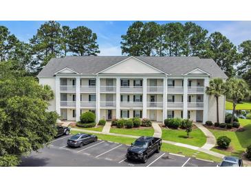 Three-story condominium building featuring private balconies, green landscaping, and convenient parking at 5040 Windsor Green Way # 204, Myrtle Beach, SC 29579