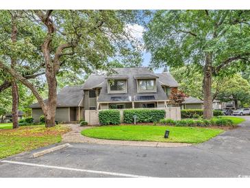 Charming condo featuring a well-maintained exterior with lush landscaping and mature trees providing shade and curb appeal at 213 Westleton Dr. # 16-D, Myrtle Beach, SC 29572