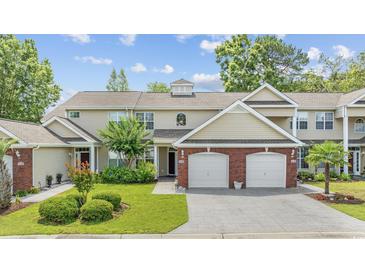 Charming exterior view of townhome showcasing manicured lawn, brick accents, and a two-car garage at 2150 Longwood Lakes Dr. # 2150, Myrtle Beach, SC 29579
