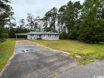 Exterior of home with large front yard, mature trees, long driveway and convenient carport at 321 Circle Heights Dr., Loris, SC 29569