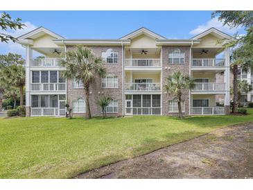 Three-story condo with brick facade, balconies, palm trees, and a well-maintained lawn at 4721 Hibiscus Dr. # 3-302, Little River, SC 29566